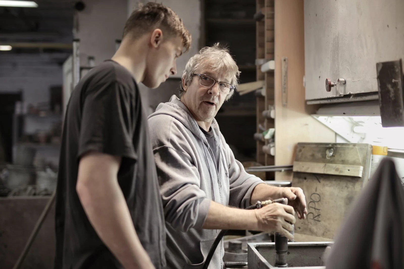 Experienced tradesman teaching a young apprentice in a workshop
